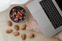 Dark chocolate brittle and walnuts on a wooden floor next to a laptop
