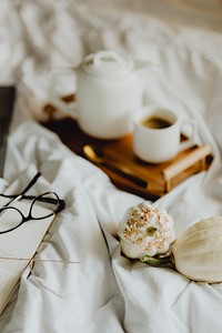 Closeup of a notebook, a cup of coffee, and white squashes in bed