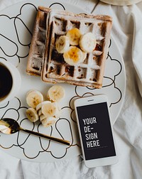 Plate of waffle with slices of banana and a cup of coffee next to a smartphone