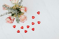 Valentine&#39;s rose bouquet with red chocolate hearts on a white marble background