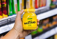 Hand holding a mustard jar in a grocery store