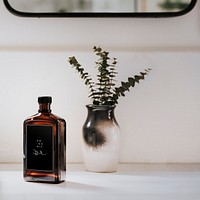 Liquid brown bottle mockup by a vase