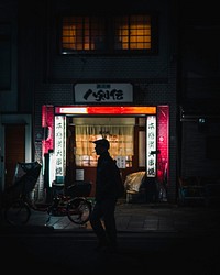 Silhouetted man smoking in front of a restaurant in Japan