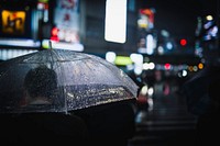 Man walking with a transparent umbrella in a city at night