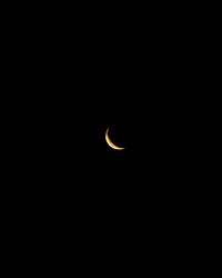 Yellow waning crescent moon in the night sky