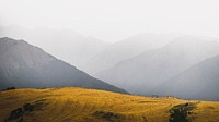 Nature desktop wallpaper background, grassland among misty mountains landscape