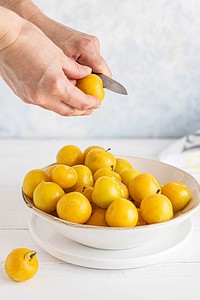 Woman slicing mirabelle plums in the kitchen