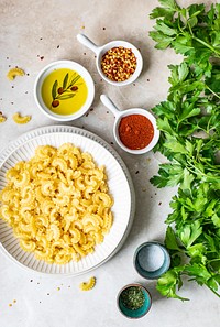 Dry pasta in a bowl surrounded by fresh ingredients