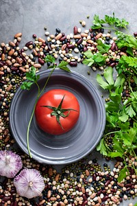 Fresh tomato in a bowl surrounded by legumes