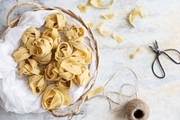 Uncooked pappardelle pasta on a wooden basket