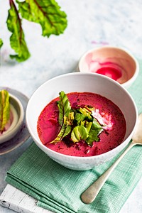 A bowl of healthy beetroot leaf soup with cream on a table