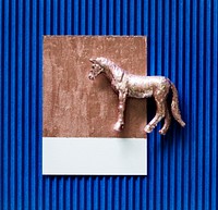 Tiny metallic horse on blue paper