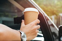 Hand holding takeaway coffee in a car