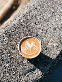 Latte art in a mug placed on a stony surface