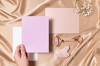 Blank pink papers with jade roller and gua sha, flay lay