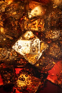 Cold carbonated drink over ice cubes in a glass close up 