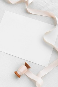 Blank white paper note with a pink ribbon roll