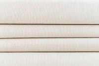 Stack of folded beige woven fabric patterned background