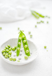 Closeup of peas in a white cup. Visit <a href="https://monikagrabkowska.com/" target="_blank">Monika Grabkowska</a> to see more of her food photography.