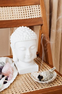 Buddha head statue by a burning sage smudge cleansing the house