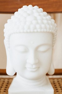 White ceramic Buddha head statue on a wooden chair