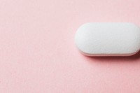 White medicinal tablet on a pink background