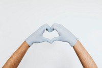Gloved hands making a heart shaped sign on a gray background