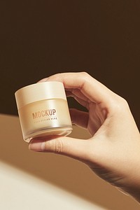 Hand holding beige cream pot mockup