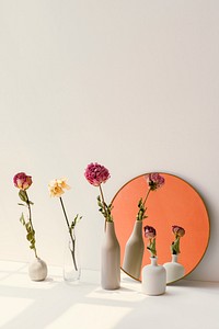 Dried flowers in minimal vases by a round mirror