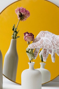 Woman in a lace glove getting a dried pink rose from a vase