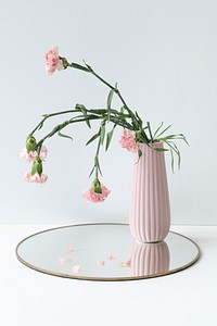 Withered pink carnation in a pink vase on a shiny tray