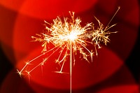 Burning sparkler design element on a red bokeh background