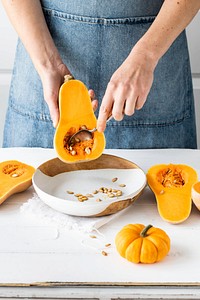 Woman removing butternut squash seeds in kitchen