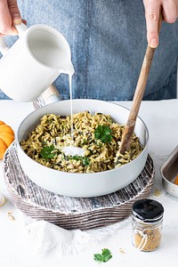 Woman pouring coconut milk over curry rice and coriander