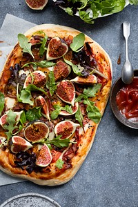 Pizza with tomatoes ham mozzarella and figs flat lay