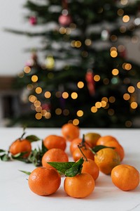 Clementines on a table by a Christmas tree