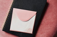 Pink envelope mockup on a black notebook 