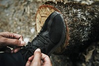 Man tieing his shoelaces on a tree stump