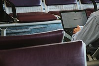 Man using a laptop on a leather seats in waiting area at the airport