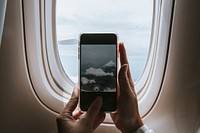 Woman capturing clouds from the plane window with her phone