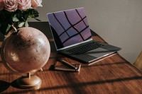 Laptop by a globe and fresh roses