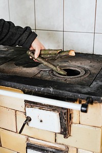 Woman putting sticks into the stove