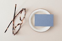 Blank blue business card on a plate with glasses