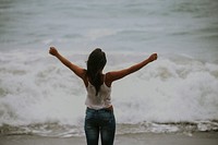 Woman standing with open arms at beach