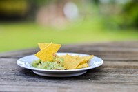 Free tortilla chip dip into sauce image, public domain food CC0 photo.