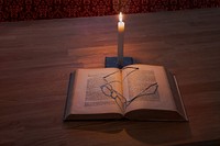 Free glasses on open book with candle lit photo, public domain CC0 image.