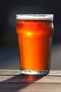 Free beer pint glass close up on wooden table photo, public domain beverage CC0 image.