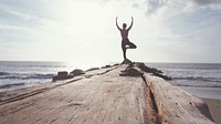 Woman doing yoga post on cliff facing ocean, free public domain CC0 photo.