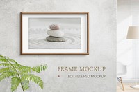 Wooden picture frame mockup psd with zen stones photo on the wall interior concept