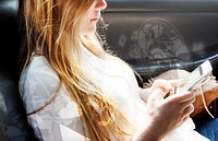 Young blond girl texting in a car